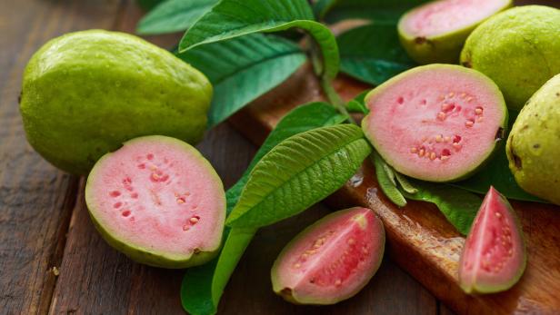Aufgeschnittene Guaven: Rosa Fruchtfleisch in einer grünen, zitrusähnlichen Schale