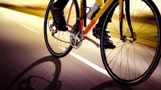 Ein Radfahrer fährt mit hoher Geschwindigkeit auf einer asphaltierten Straße.