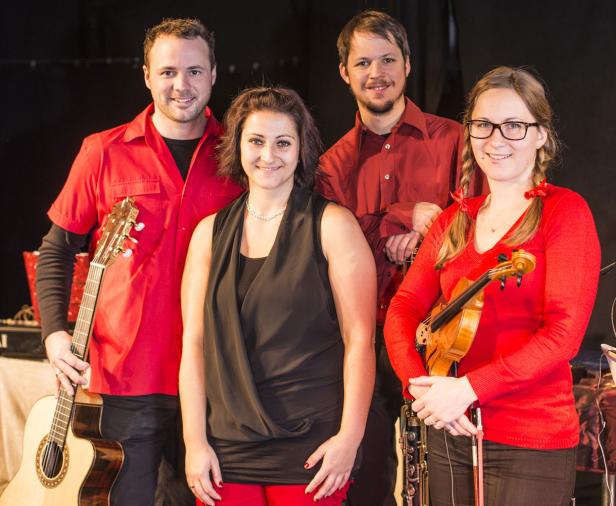 Eine vierköpfige Band posiert mit ihren Instrumenten für ein Gruppenfoto.
