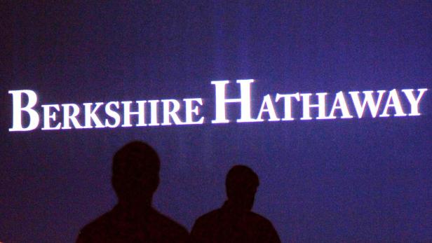 Das Logo von Berkshire Hathaway vor den Silhouetten von zwei Personen.
