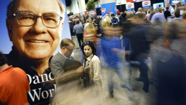 Ein großes Poster von Warren Buffett auf einer belebten Veranstaltung.