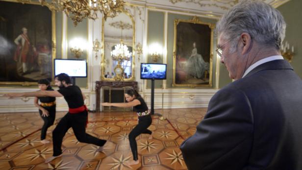 Eine Gruppe von Tänzern führt eine Performance in einem opulenten Saal auf.