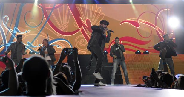 Die Backstreet Boys treten vor einem jubelnden Publikum auf einer Bühne auf.