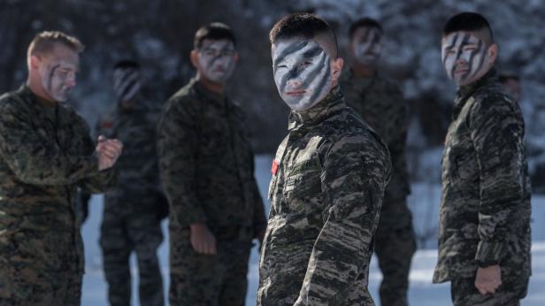 Eine Gruppe Soldaten mit Tarnfarbe im Gesicht steht im Schnee.