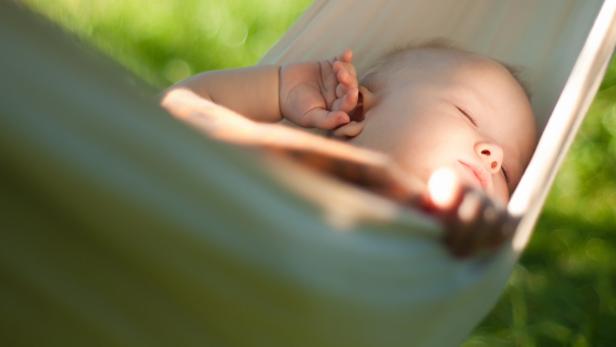Ein Baby schläft friedlich in einer Hängematte.