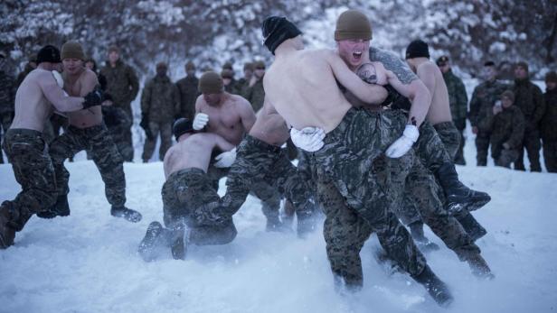 Halbnackte Soldaten ringen im Schnee, während andere in Uniform zusehen.