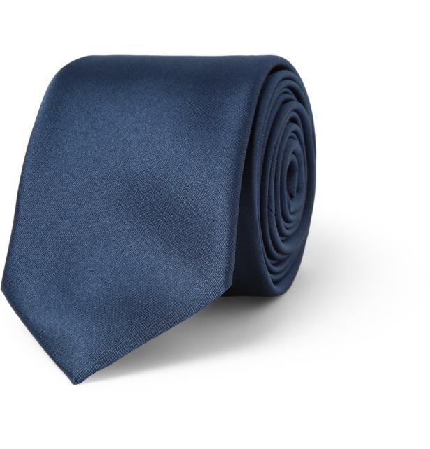 Eine marineblaue Krawatte, die aufgerollt auf einem weißen Hintergrund liegt.