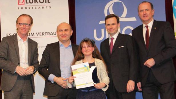 Eine junge Frau hält eine Urkunde, umgeben von vier Männern in Anzügen.