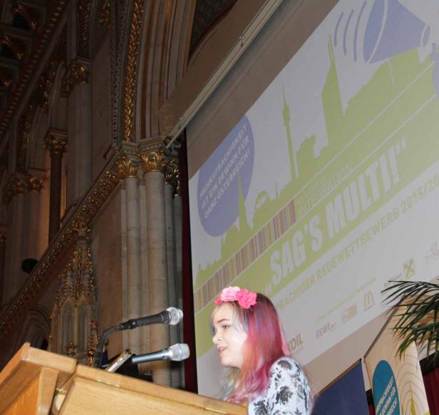 Ein Mädchen mit Blumenkranz hält eine Rede bei „Sag’s Multi!“.