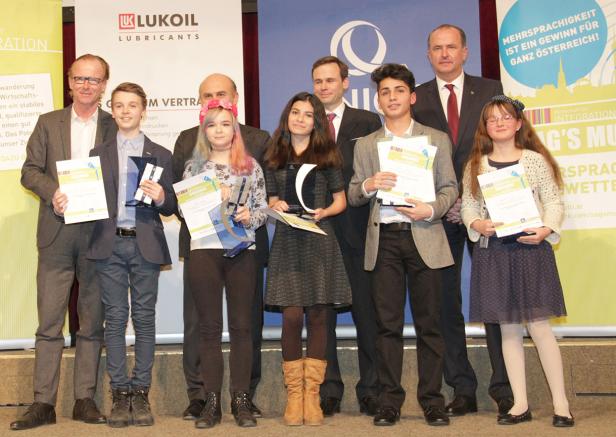 Eine Gruppe von Jugendlichen und Erwachsenen posiert mit Urkunden und Preisen auf einer Bühne.