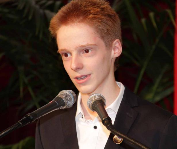 Ein junger Mann mit roten Haaren spricht in zwei Mikrofone.