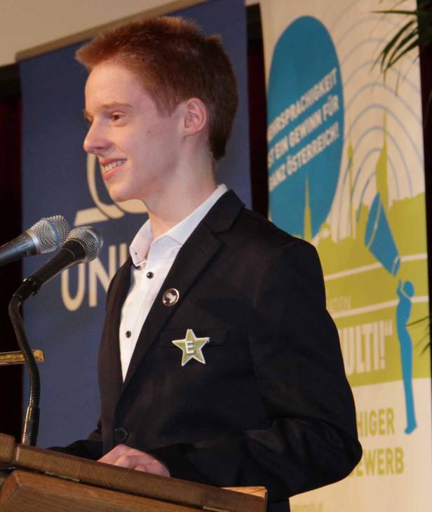 Ein junger Mann mit roten Haaren hält eine Rede an einem Rednerpult.