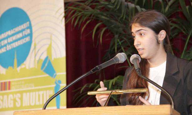 Eine junge Frau spricht bei einer Veranstaltung am Rednerpult.