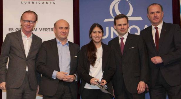 Eine Gruppe von fünf Personen posiert vor einem blauen Hintergrund mit dem UNOQA-Logo.