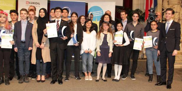 Eine Gruppe Jugendlicher steht auf einer Bühne und hält Urkunden und Pokale.