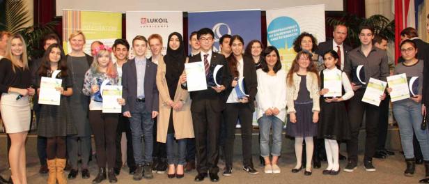 Eine Gruppe von Preisträgern posiert mit ihren Urkunden vor Bannern.