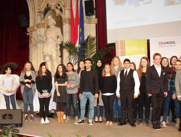 Eine Gruppe Jugendlicher steht auf einer Bühne vor Flaggen und Bannern.