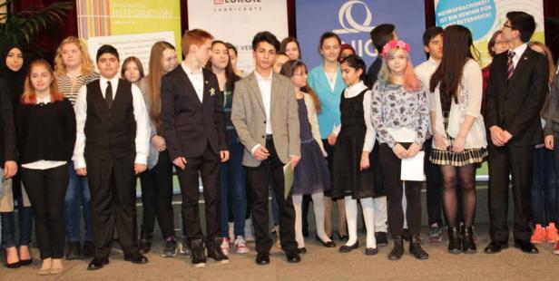 Eine Gruppe Jugendlicher steht auf einer Bühne vor verschiedenen Bannern.