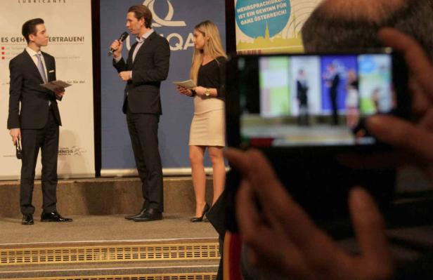 Drei Personen stehen auf einer Bühne, während eine weitere Person ein Foto macht.