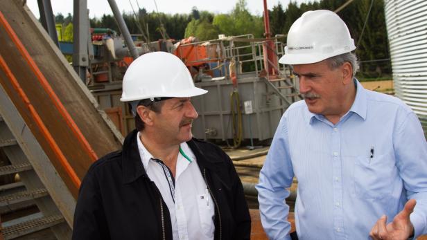 Zwei Männer mit Schutzhelmen unterhalten sich vor einer Industrieanlage.