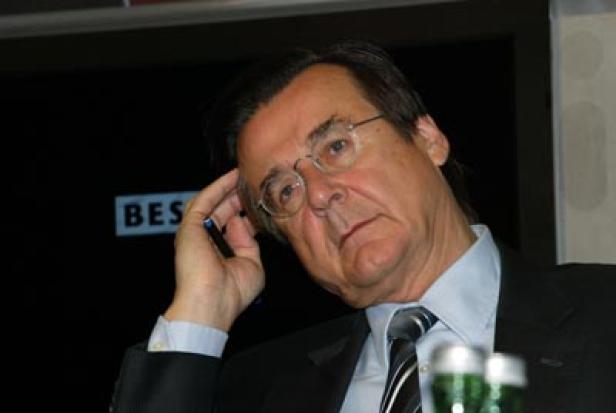 Ein Mann mit Brille und Anzug sitzt nachdenklich da.