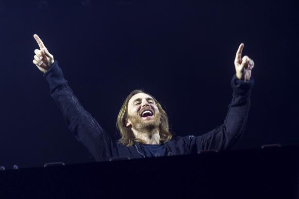 David Guetta legt mit erhobenen Armen bei einem Auftritt auf.