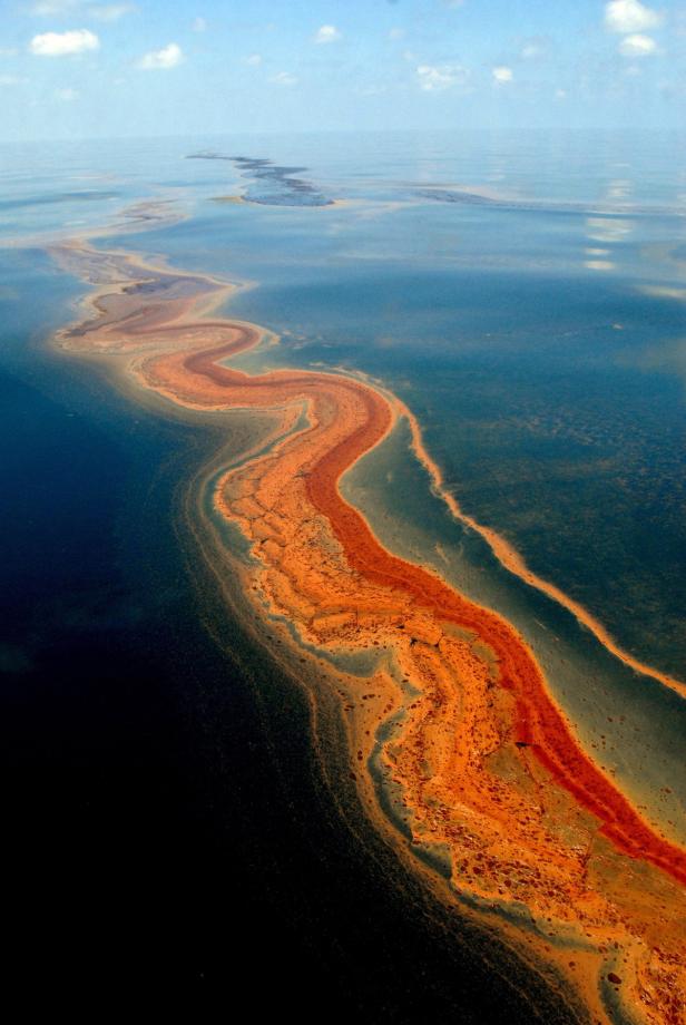 Eine orangefarbene Ölspur schlängelt sich durch das blaue Meer.