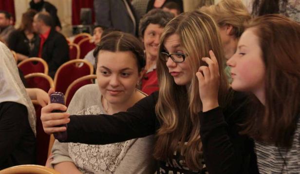 Drei junge Frauen machen ein Selfie in einem Raum mit rotem Gestühl.