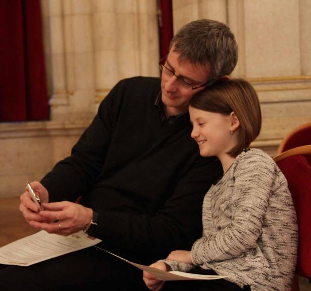 Ein Vater und seine Tochter sitzen zusammen und schauen auf ein Dokument.