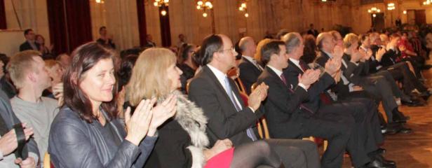 Ein Publikum applaudiert während einer Veranstaltung in einem festlichen Saal.