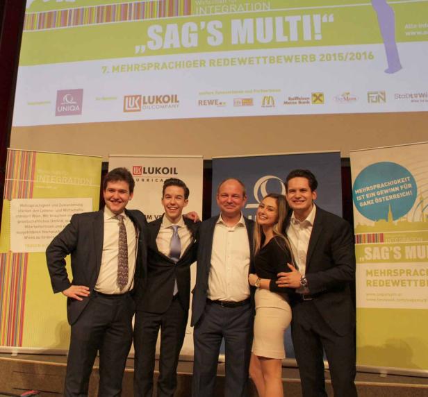 Eine Gruppe von Personen posiert vor einem Banner für den „Sag's Multi!“ Redewettbewerb.