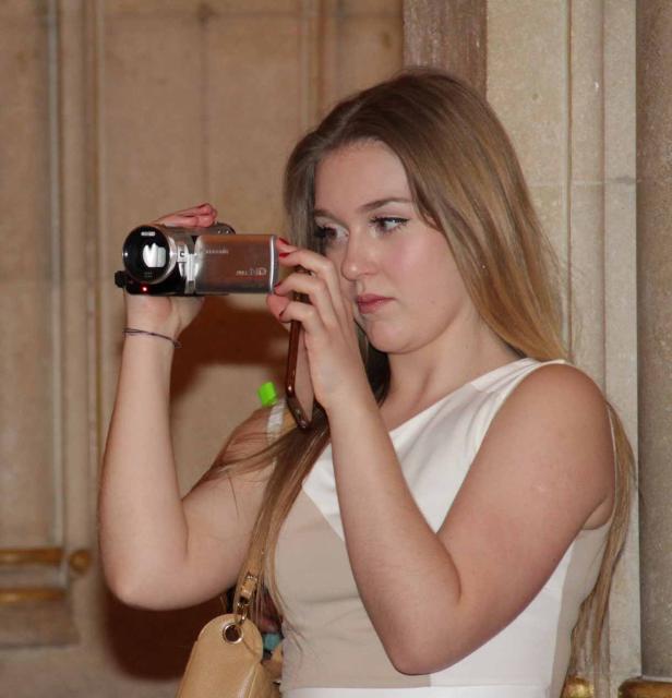 Eine junge Frau filmt mit einer kleinen Videokamera.