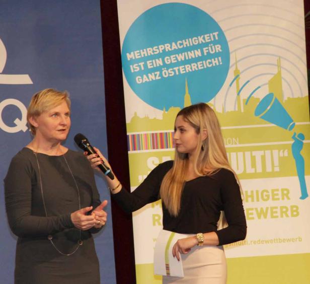 Eine Frau interviewt eine andere Frau vor einem Banner zum Thema Mehrsprachigkeit.