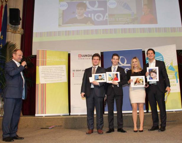 Eine Gruppe von Personen hält gerahmte Bilder auf einer Bühne.