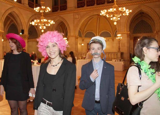 Personen in Kostümen posieren in einem festlichen Saal mit Kronleuchtern.