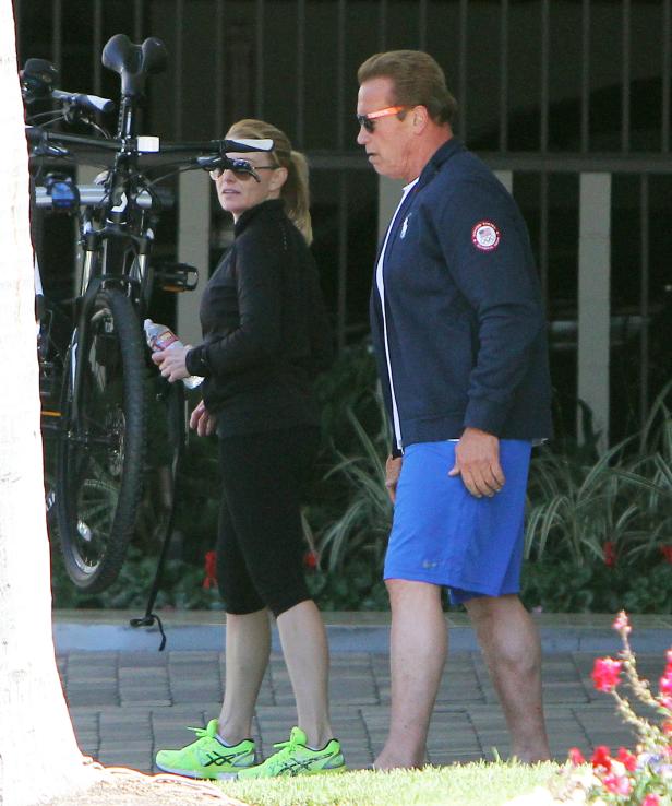 Arnold Schwarzenegger und eine Frau gehen mit einem Fahrrad spazieren.