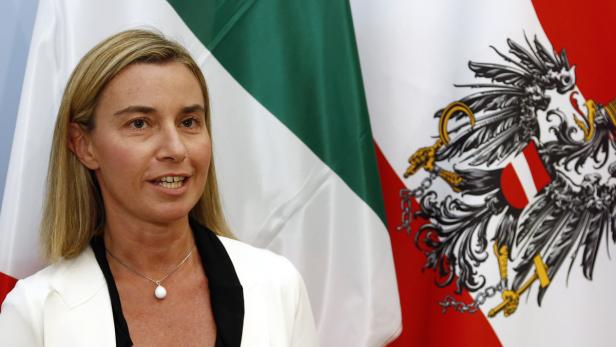 Eine Frau steht vor den Flaggen von Italien und Österreich.