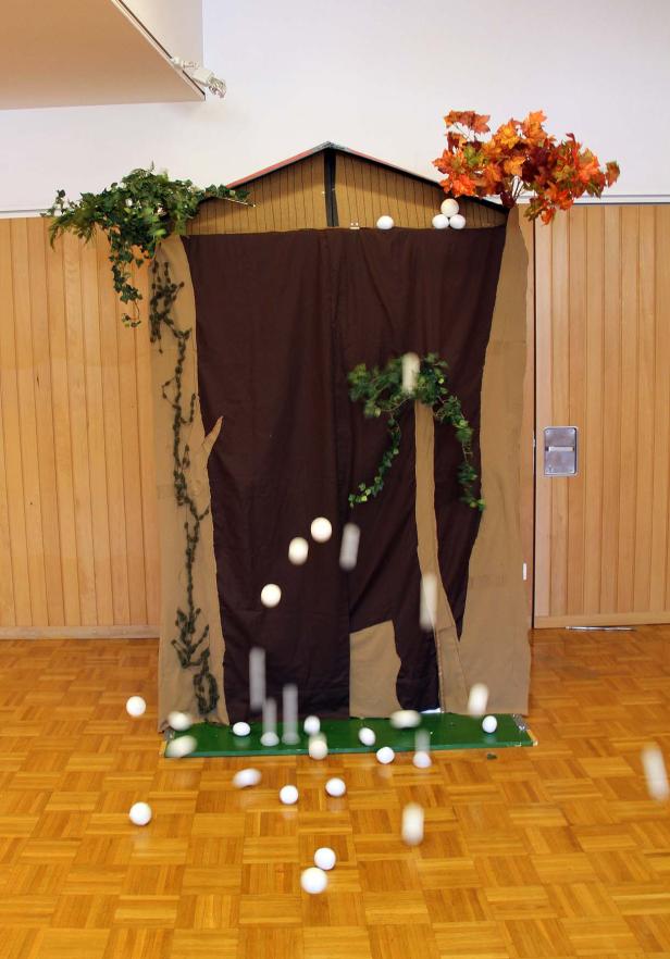 Eine improvisierte Bühne mit fallenden weißen Bällen im Innenraum.