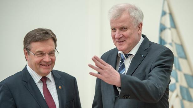 Horst Seehofer gestikuliert neben einem Mann mit Brille vor der bayerischen Flagge.