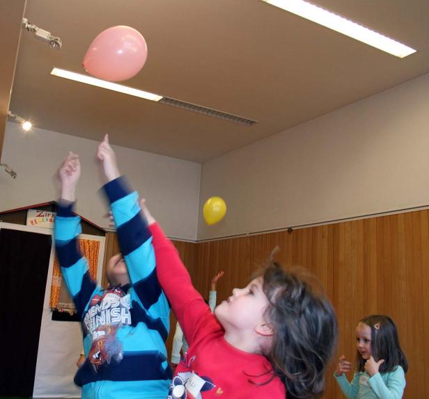 Mehrere Kinder versuchen, Ballons in einem Raum zu berühren.