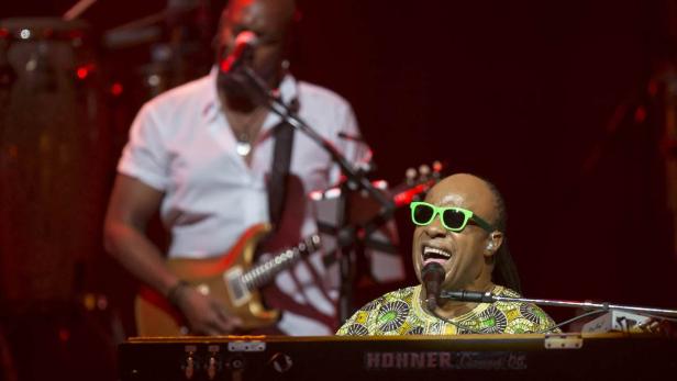 Stevie Wonder spielt Klavier und singt mit grüner Sonnenbrille.