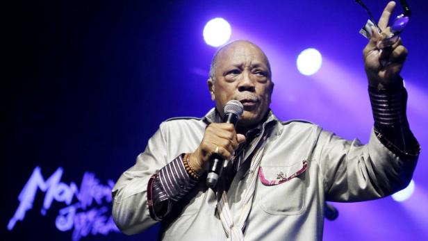 Quincy Jones singt während eines Auftritts und hält eine Brille in der Hand.