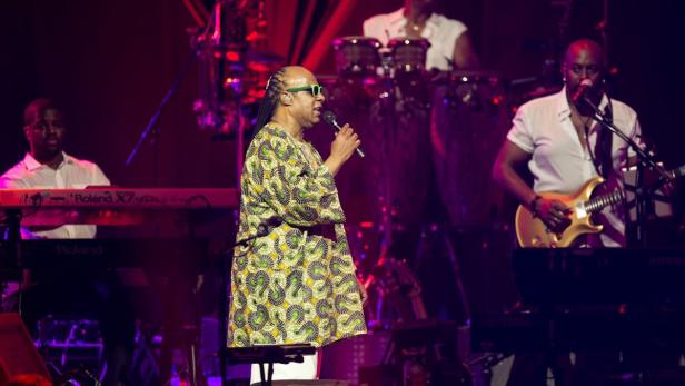 Stevie Wonder singt auf der Bühne mit seiner Band.