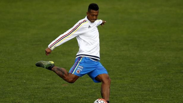 Ein kolumbianischer Fußballspieler schießt einen Ball auf einem grünen Rasen.