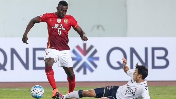 Ein Fußballspieler in rotem Trikot dribbelt den Ball, während ein anderer am Boden liegt.