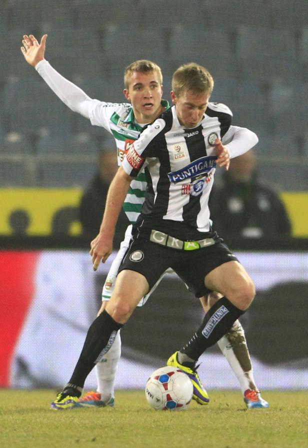 Zwei Fußballspieler kämpfen um den Ball während eines Spiels.
