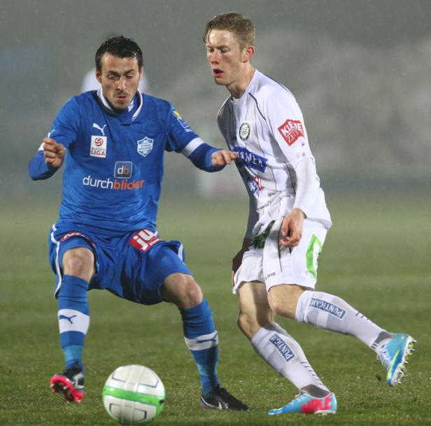 Zwei Fußballspieler kämpfen um den Ball während eines Spiels.