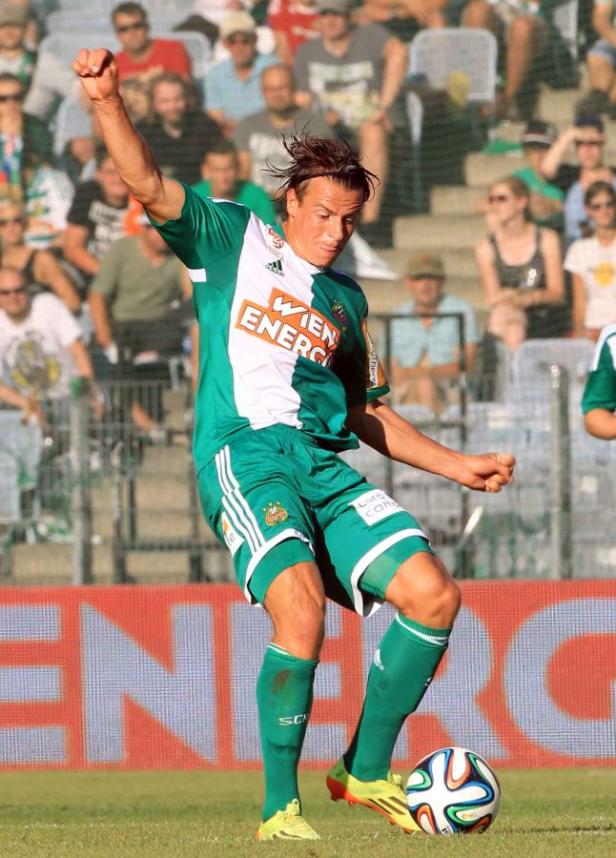 Ein Fußballspieler in Grün und Weiß schießt einen Ball.