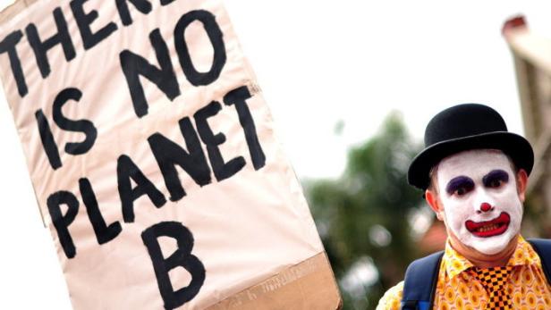 Durban, Weltklimagipfel, Umweltschutz Ein als Clown geschminkter Mann steht neben einem Schild mit der Aufschrift „There is no Planet B.“.