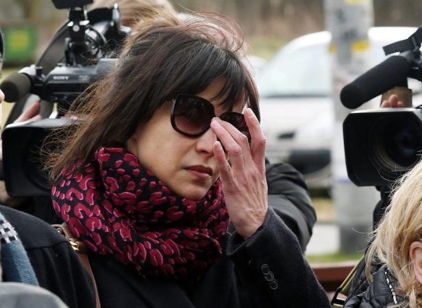 Eine Frau mit Sonnenbrille und einem Schal mit Tiermuster steht vor mehreren Kameras.